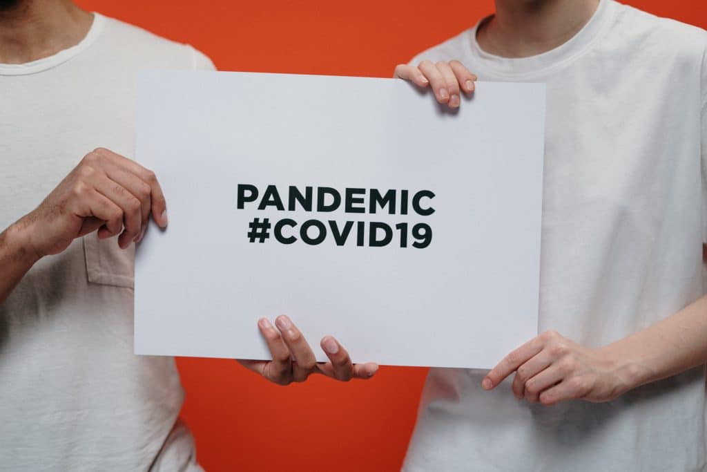 People-Holding-White-Paper-With-Pandemic-Covid19-Text-scaled-1