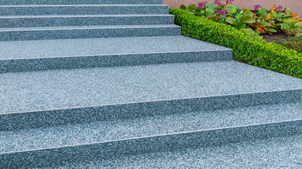 Granite outdoor steps with greenery and flowers nearby.