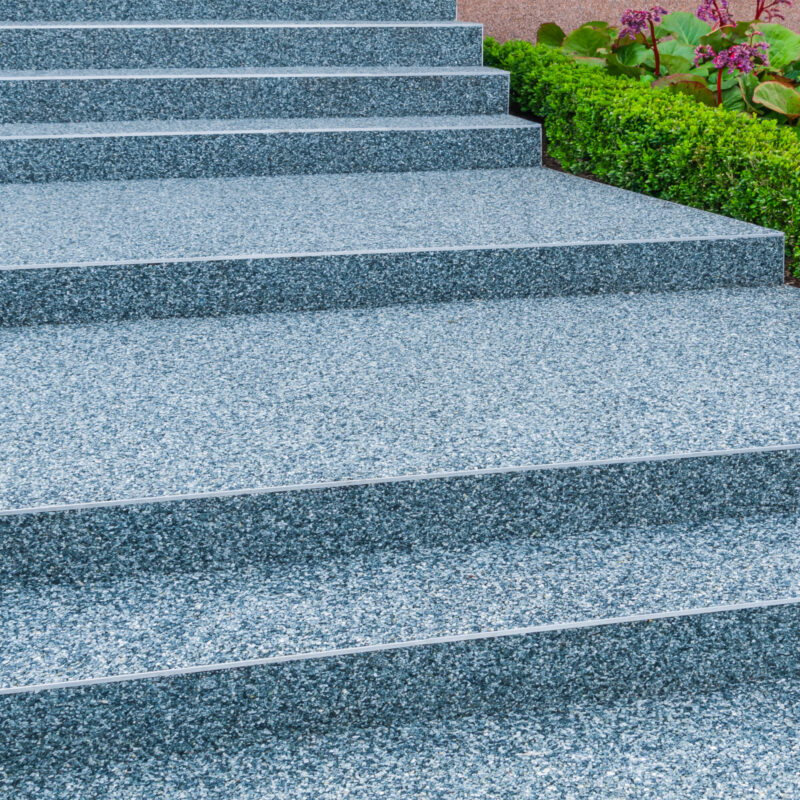 Granite outdoor steps with greenery and flowers nearby.