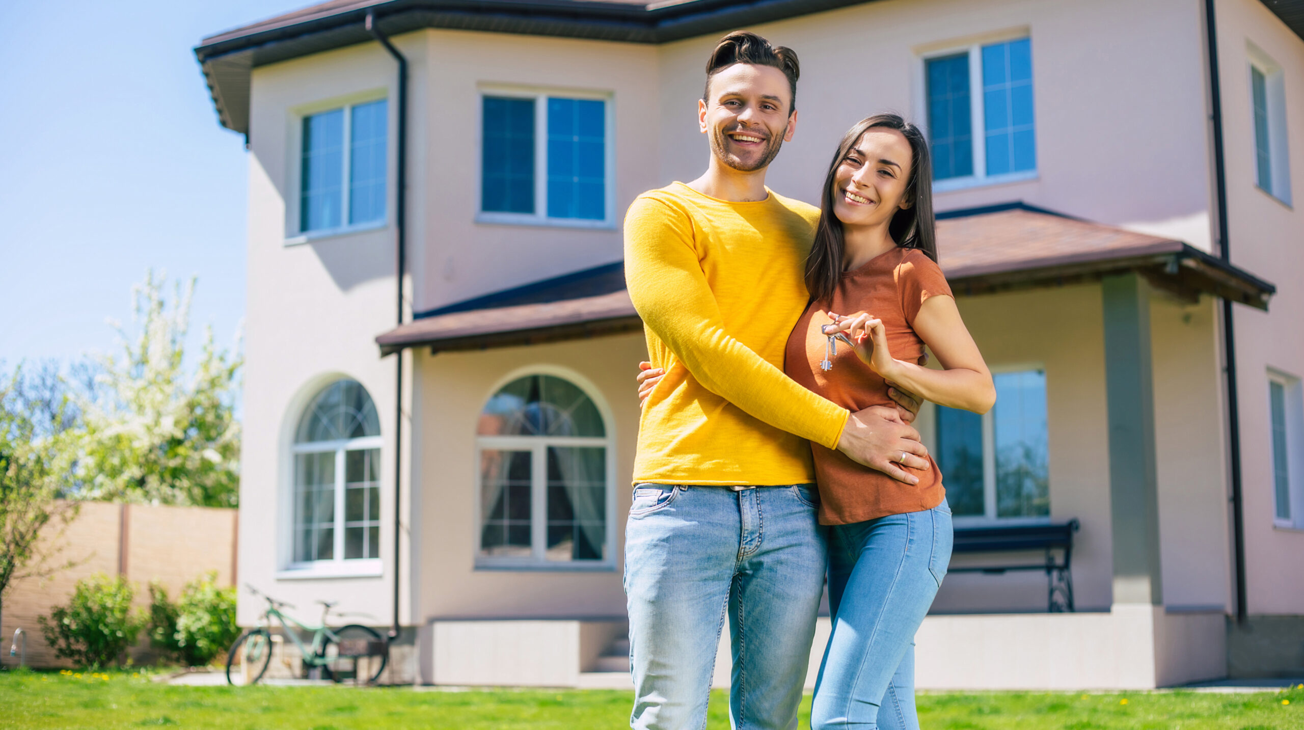 Happy couple holding house keys outside new home
